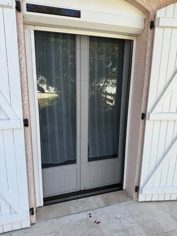 Moustiquaire accordéon blanche posée sur une porte-fenêtre